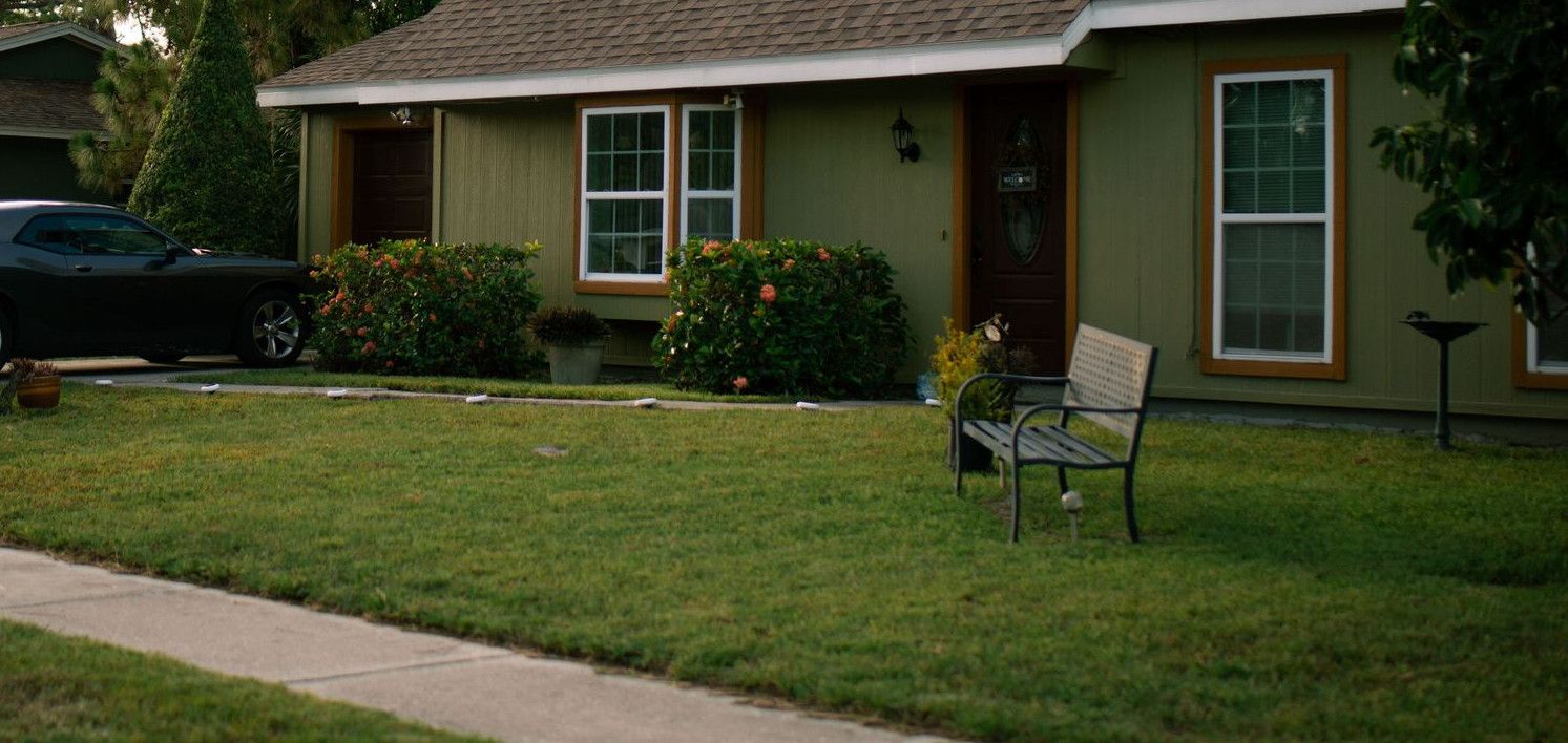 A beautiful suburban home with a well-maintained green lawn and parked car, highlighting residential comfort.